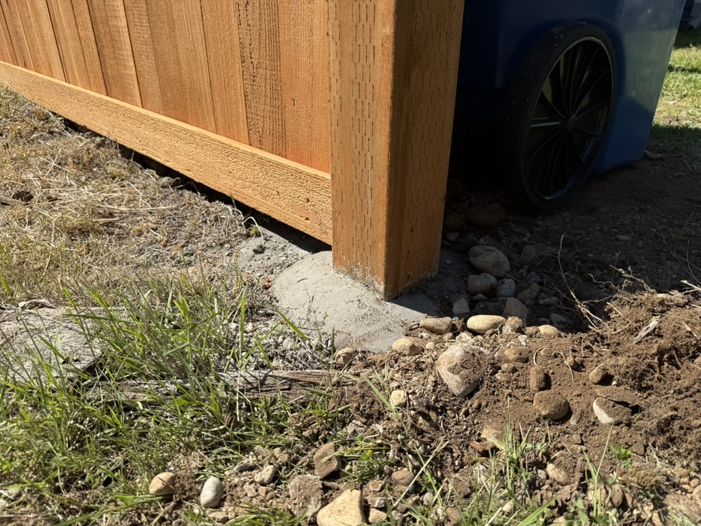 Mounded concrete footing with a smooth dome shedding water away from the post