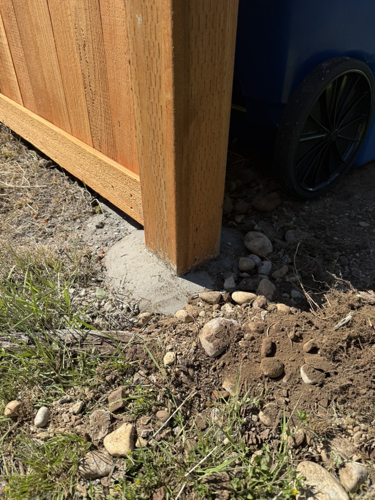 Detail of an exposed concrete footing shaped to drain water away from the wood post